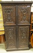 A 19th Century carved cupboard with carved pediment above two panelled cupboard doors with centre