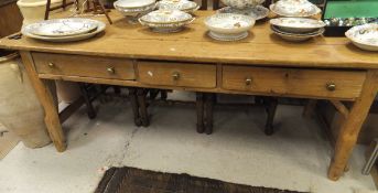 A pine plank top farmhouse dining table with three drawers to the top on rough cut legs