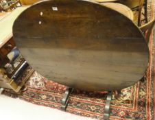 A continental oval oak tilt top Vintners table on trestle base