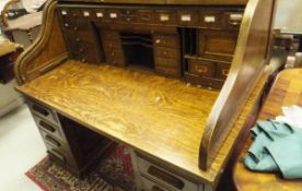 An oak roll top desk, the tambour front enclosing a selection of open compartments and drawers,