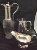 A white metal mounted circa 1900 claret jug with engraved base, raised on a circular foot,
