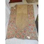 A crewel work style prayer rug of floral design in pink, orange and teal,