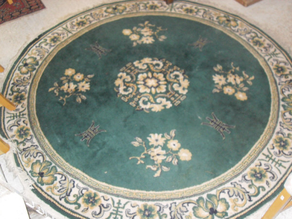 A Chinese style circular rug, the plain green ground with floral sprays and Chinese symbols,