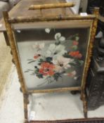A late Victorian bamboo framed and painted glass panelled fire screen with floral decoration
