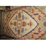 A Persian rug with centre medallion on a green and salmon pink ground with floral spray decoration