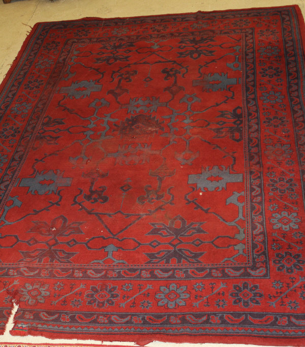 A Donegal carpet, the central panel set with scrolling decoration on a red ground,