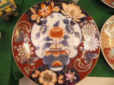 A Chinese Imari charger with centre field decorated with a vase of flowers within an oxide red and