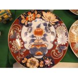 A Chinese Imari charger with centre field decorated with a vase of flowers within an oxide red and