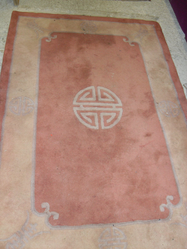 A modern Chinese super wash rug, the central panel set with Chinese symbol on a terracotta ground,