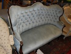 A late Victorian mahogany framed buttoned upholstered salon sofa on cabriole front legs to castors