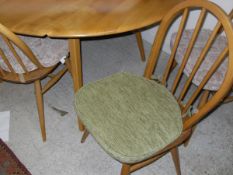 An Ercol elm oval drop-leaf dining table together four chairs and one near matching chair