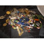A box containing various costume jewellery including necklaces, brooches, scent funnel,