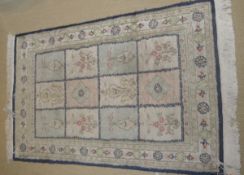 A silk rug, the central panel set with three rows of floral decorated panels, within a sky,