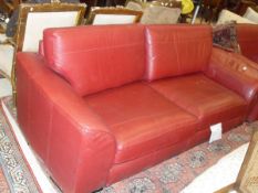 A modern red leather upholstered three seat sofa and matching arm chair