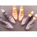 A collection of three pairs of Berluti gentleman's shoes comprising two black pairs and one brown,