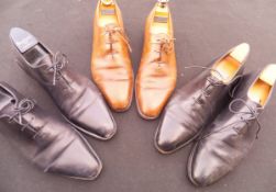 A collection of three pairs of Berluti gentleman's shoes comprising two black pairs and one brown,