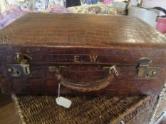 A vintage crocodile skin suitcase with brass fittings inscribed "E.W.