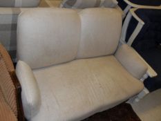 A Victorian upholstered two seat sofa raised on three turned and ringed front legs to horn castors