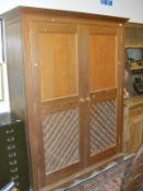 A modern pitch pine food cupboard with two ventilated doors enclosing shelving