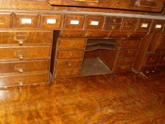 An oak roll top desk, the tambour front enclosing a selection of open compartments and drawers,