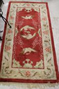 A Chinese silk rug, the central panel set with cranes on a red ground within a cream,