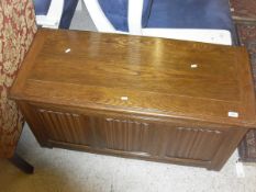 A modern oak coffer with linen fold carved three panel front on stile supports