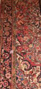 An Eastern rug, the central panel with all over floral motifs on a red ground within a stepped red,