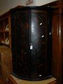 An 18th Century lacquered and chinoiserie decorated hanging bow fronted two door corner cupboard