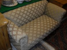 A circa 1900 sofa in a pale gold brocade upholstery on stained oak legs with single drop arm