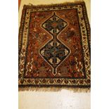 A Shiraz rug, the central panel set with two joined lozenge shaped medallions on a brown ground,
