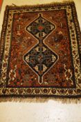 A Shiraz rug, the central panel set with two joined lozenge shaped medallions on a brown ground,