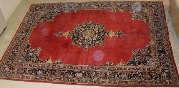 A Persian carpet, the central panel set with central flowerhead designed medallion on a red ground,