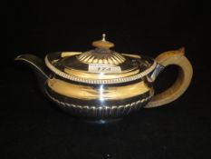 A Georgian silver teapot of Squat form with half reeded base and wooden handle and finial (by