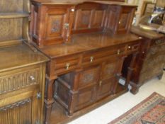 An Edwardian oak sideboard with two cupboard doors with carved panels above a base of three drawers