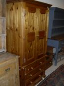 A modern pine wardrobe with two doors over three drawers and a pine cabinet with two shelves over a
