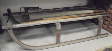 A vintage wooden sledge with iron runners, together with a shooting stick,