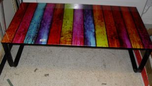 A glass topped coffee table on a painted metal frame