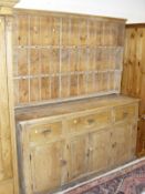A pine dresser the two tier boarded plate rack over three drawers and four cupboard doors on a