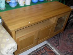 A modern oak lounge unit with assorted cupboard doors and open recess,
