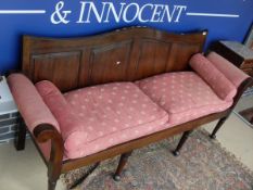 A mahogany framed Georgian style sofa with scrolled arms and pink ground upholstery