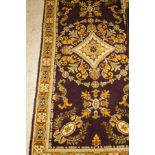 A Persian style rug, the central panel set with floral decorated medallion on an aubergine ground,