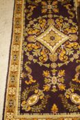 A Persian style rug, the central panel set with floral decorated medallion on an aubergine ground,