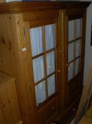 A modern pine wardrobe with two glazed doors above two drawers, two bedside chests,