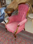 A Victorian rosewood framed spoon back arm chair in a pink button back upholstery and cabriole legs