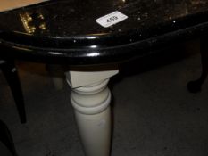 A black marble topped dining table with rounded corners on a cream painted base