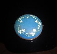 A Ruskin ceramic brooch decorated with floral motifs on a blue ground, stamped "Ruskin" to back,