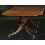 A mahogany rounded rectangular twin pillar dining table in the George III taste with single extra
