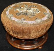 A Victorian needlework and bead decorated circular footstool on a galleried mahogany base,