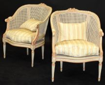 A pair of painted framed and caned bergères in the Louis XVI taste,