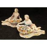 A pair of 19th Century Meissen figures as a recumbent gentleman and lady with baskets of flowers,